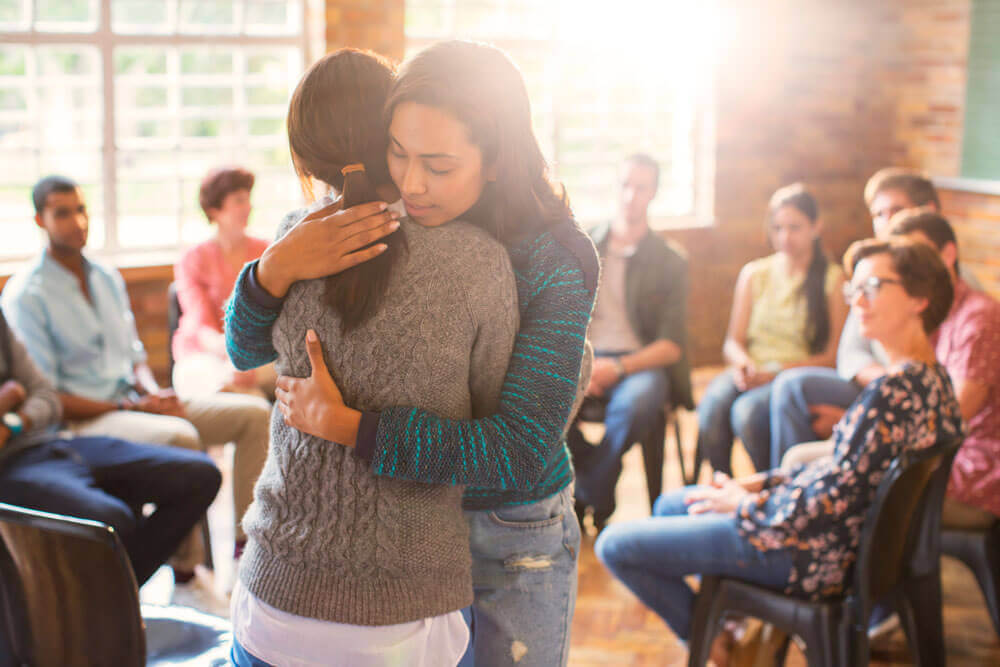 two women hug at a support group 