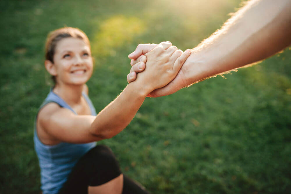 a woman clasps the hand of someone off camera 