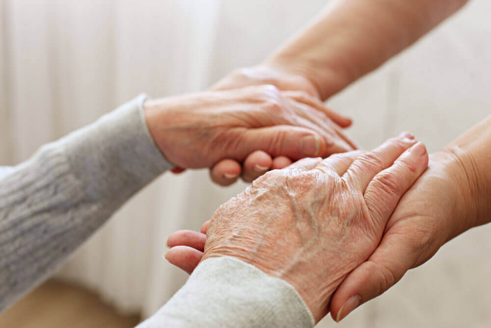 An old woman clasps hands with someone else 