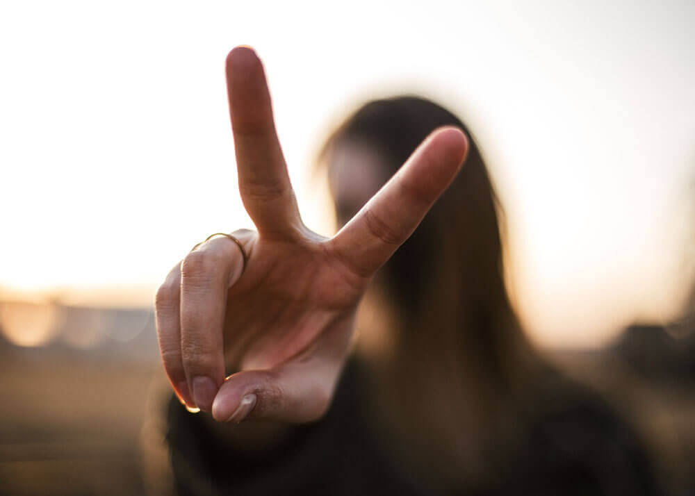 a woman makes the peace sign to the camera 