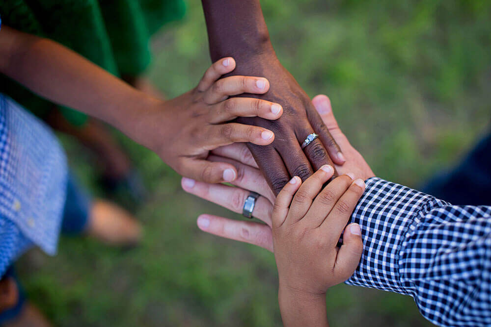 A group of people clasp hands together 
