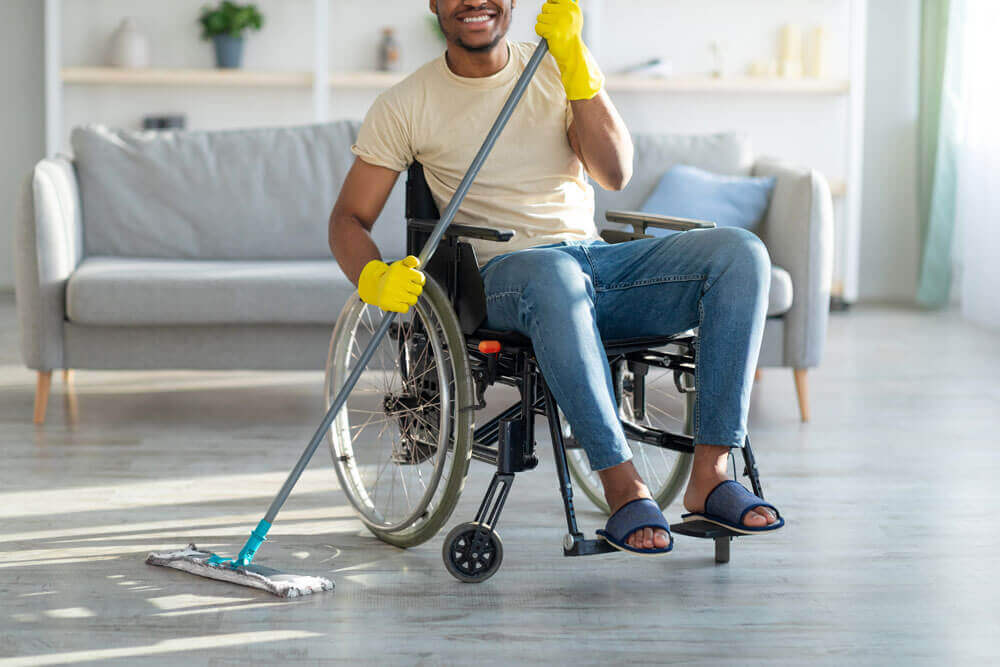 daily-living-skills a man in a wheelchair cleans his home