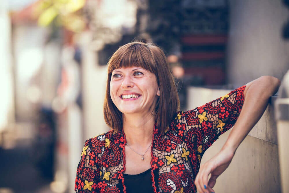 A woman smiles and leans against a wall