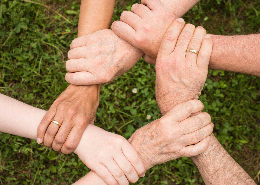 a variety of hands clasping each other's wrist 